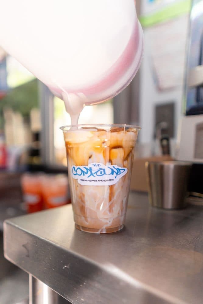 Cold foam pouring into a Compound iced latte